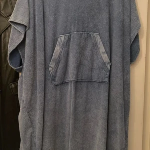 Blå frottéponcho från Finlayson - Säljer en bekväm blå frottéponcho från Finlayson. Perfekt för att hålla sig varm efter badet. Ponchon har en stor ficka framtill och en praktisk huva. Perfekt för stranden eller poolen! 🏖️