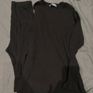 Svart ribbad tröja och byxa från Fashion Design - Säljer en svart ribbad tröja och byxa från Fashion Design. Tröjan har långa ärmar och en bekväm passform. Perfekt för en stilren look.