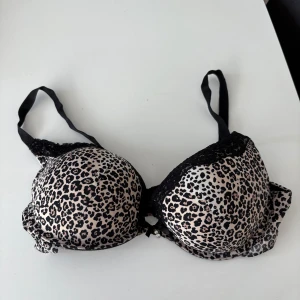 Leopardmönstrad bh med spetsdetaljer - Säljer en snygg leopardmönstrad bh med svarta spetsdetaljer. Den har justerbara axelband och en bekväm passform. Perfekt för att ge en extra touch till din outfit! Står ej storlek men är som 85C