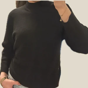 Svart tröja med polokrage - Säljer en stilren svart tröja från H&M. Tröjan har en klassisk design med långa ärmar och en halv polokrage. Perfekt för en minimalistisk look. Storlek M men passar även XS-S. Armarna är kortare i modellen och slutar ca i mitten på underarmen. 