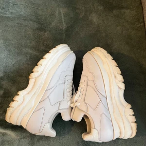 Vita sneakers med chunky sula - Snygga vita sneakers med en rejäl chunky sula och snörning. Perfekta för en trendig look. Tillverkade i skinn för en stilren finish.