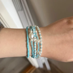 Turkost och vitt pärlarmband - Charmigt armband med flera rader av turkosa och vita pärlor. Armbandet har en mix av små turkosa pärlor och vita pärlor som ger en fräsch och somrig känsla. Perfekt för att lägga till en färgklick till din outfit. Alla för 60kr eller 29kr/st 