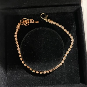 Guldarmband med glittriga stenar - Elegant guldarmband med små glittriga stenar som ger en lyxig känsla. Perfekt för att lägga till lite extra bling till din outfit. 15 cm som kortast.