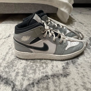 Nike Air Jordan i grått och vitt - Säljer ett par stilrena Nike Air Jordan 1 sneakers i grått och vitt. Skorna har klassisk snörning och den ikoniska Air Jordan-loggan på sidan. Perfekta för dig som vill ha en sportig och trendig look.