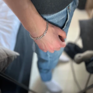 Silverfärgat armband - Snyggt silverfärgat armband med en klassisk kedjedesign. Perfekt för att ge en stilren touch till din outfit. Armbandet har en justerbar kedja för att passa olika storlekar.