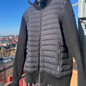 Moncler cardigan Black Label - Säljer en Cardigan storlek XL men den sitter lite mindre. Jag är 185cm men den för stor mig efter en operation då jag gick ned väldigt mycket i vikt. Fint skick förut en liten skavank på höger sida fram arm (se bild 2). Finns i Stockholm, inner stan