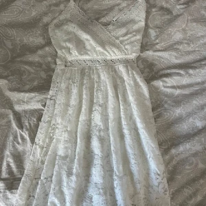 Vit spetsklänning från Hailys - Säljer en vacker vit spetsklänning från Hailys i storlek XS. Klänningen har en omlott-design med smala axelband och spetsdetaljer. Perfekt för sommaren! 🌸