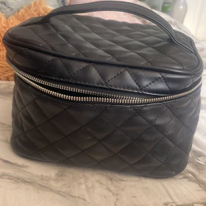 Svart quiltad väska - Snygg svart quiltad väska med dragkedja och handtag. Perfekt för att hålla ordning på dina saker. Har försökt tvätta den så bra jag kan. Skriv om man har frågor ❤️