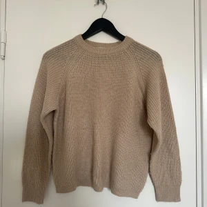 Beige stickad tröja - Beige stickad tröja med rund hals och långa ärmar. 