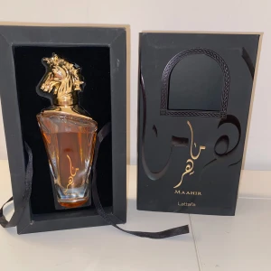 Maahir Parfym från Lattafa - Elegant parfym från Lattafa med en unik flaska prydd av ett gyllene hästhuvud. Flaskan har en stilren design med klara linjer och en varm bärnstensfärgad vätska. Förpackningen är svart med dekorativa detaljer. Perfekt för den som söker en distinkt och lyxig doftupplevelse. Den är 100ml och det är ungefär 79ml kvar