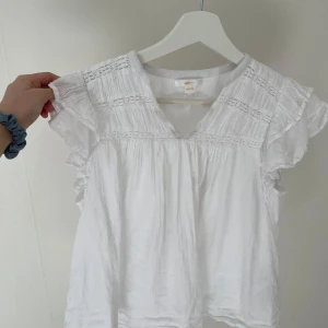 Vit blus från Gina Tricot - Säljer en söt vit blus från Gina Tricot med fina spetsdetaljer och volanger vid ärmarna. Super fin på somarn! Säljer då den tyvärr är lite för kort på mig för min smak! Storlek 146/152 men skulle säga att den passar xxs
