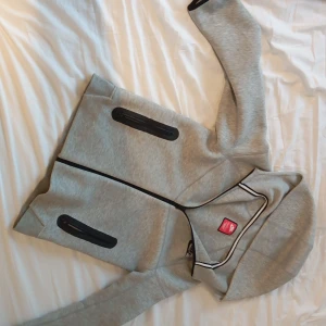 Grå Nike Tech - Säljer en grå Nike tech. Den har en bekväm passform och är tillverkad i mjukt material. Storlek 147-158 cm