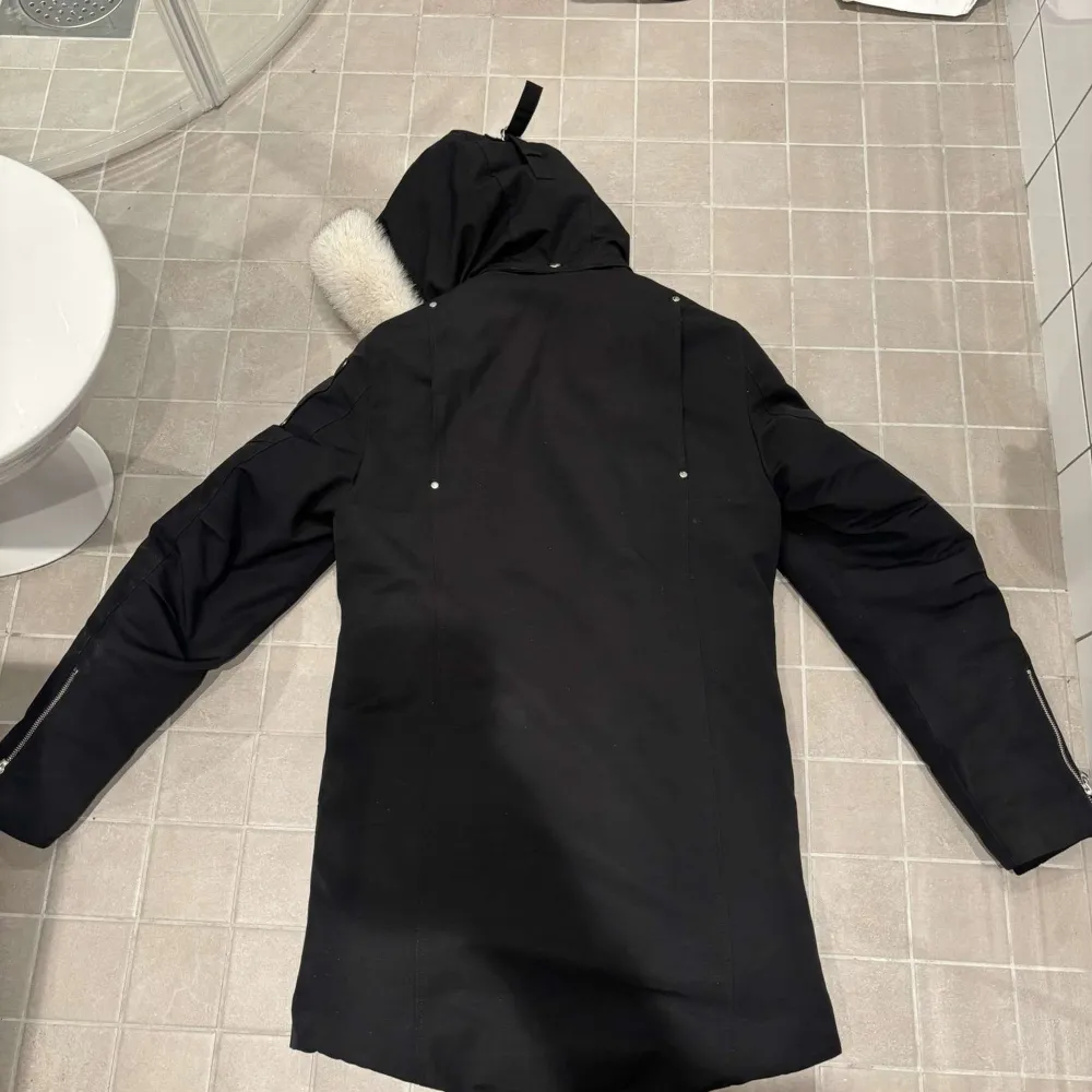 Säljer en svart dunjacka från Moose Knuckles med pälskantad huva. Jackan har dragkedja och knappar framtill samt flera praktiska fickor. Perfekt för kalla vinterdagar. Kommer i sitt skydd/ påse. Takit.