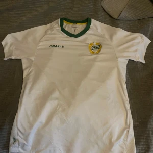 Vit fotbollströja från Craft Bajen  - Säljer en vit fotbollströja från Craft med gröna detaljer och korta ärmar. Tröjan har en klubbemblem på bröstet och nummer 3 på ryggen. Perfekt för fotbollsfans! ⚽Bajen 