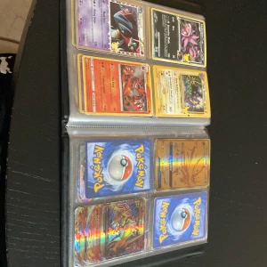 Pokémonkort samling i pärm - Stor samling av Pokémonkort i en pärm. Innehåller flera holografiska och V-kort som Flying Pikachu V, Dodrio V, Orbeetle V och Zamazenta V. Perfekt för samlare eller Pokémon-entusiaster som vill utöka sin kollektion. Kortens skick är varierande och pärmen ger bra skydd och organisering.