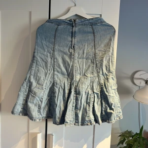 Ljusblå jeanskjol - Säljer en ljusblå jeanskjol med en avslappnad passform. Kjolen har en lång design och är perfekt för en casual look. Den är tillverkad i ett mjukt denimtyg som ger en bekväm känsla.