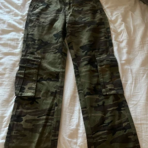 Camouflage cargobyxor - Snygga cargobyxor i klassiskt camouflagemönster. Byxorna har flera praktiska fickor och en loose passform som ger en avslappnad stil. Perfekta för en cool och bekväm Y2k look.