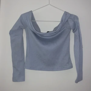 Ljusblå ribbad offsholder topp från H&M Divided - Säljer en stilren ljusblå ribbade offsholder topp från H&M Divided med långa ärmar och en bred krage. Perfekt för en avslappnad look. Passar bra till jeans eller kjol.💙