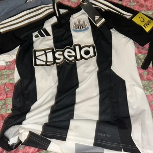 Svartvit randig Newcastle United fotbollströja - Säljer en svartvit randig Newcastle United fotbollströja med Alexander Isak , nummer 14 på ryggen från Adidas. Tröjan har korta ärmar den har också etikett för aldrig använd. Vill inte ha den eftersom den är för stor. Vann den på en turnering. DEN ÄR RIKTIG KAN TILL OCH MED DUBBELKOLLAS PÅ QR KOD
