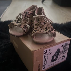 Leopardmönstrade sandaler från Zara - Söta sandaler från Zara med leopardmönster och snörning framtill. De har en dragkedja bak för enkel på- och avtagning. Perfekta för små fötter som vill ha stil.