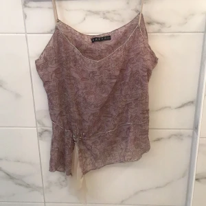 Mönstrad topp från Kaffe - Säljer en elegant mönstrad topp från Kaffe i en mjuk beige ton. Toppen har en v-ringning och är dekorerad med subtila detaljer som ger en extra touch. Perfekt för en stilfull look.