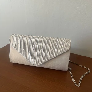 Kuvertväska - Snygg silvrig kuvertväska från JJ's House med avtagbart axelband. Aldrig använd och helt ny! Perfekt till bal eller student