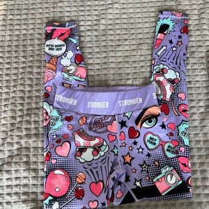 Färgglada leggings från Stronger - Snygga och färgglada leggings från Stronger med ett unikt mönster av hjärtan, stjärnor och andra pop-art-inspirerade motiv. De har en hög midja och är perfekta för träning eller en färgglad vardagslook.