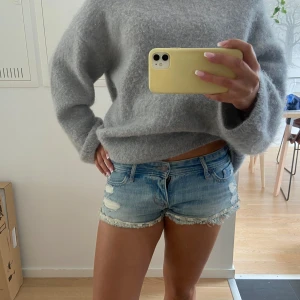 Blå jeansshorts med spets från Hollister - Snygga ljusblå jeansshorts från Hollister med låg midja, slitna detaljer och råa kanter med vit spets. Klassisk femficksmodell och knapp- samt dragkedja framtill. Perfekta för varma dagar och chill stil. Finns inte kvar att köpa! 