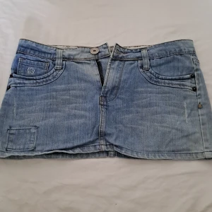 Ljusblå jeans miniskirt - Snygg jeanskjol som är kort. Men snygga detaljer på bakfickorna. Köpt från en marknad i Thailand.