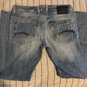 G-Star Raw jeans - G-Star Raw jeans – ljusblå, strl 34 Snygga ljusblå jeans från G-Star Raw i mycket bra skick, nästan nya. Coola slitningar och detaljer. Perfekta för en trendig streetwear-stil.