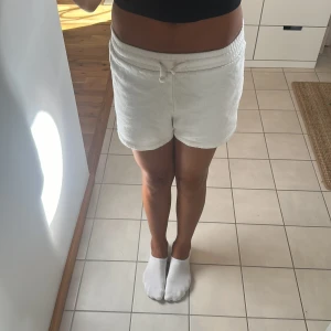 Vita shorts - Mjuka vita shorts i frotté med bekväm hög midja och snörning framtill. De har en loose passform och är perfekta för chill dagar eller när du vill ha något riktigt skönt på dig. Materialet är fluffigt och ger en avslappnad vibe. Tyvär står det inte storlek men skulle gissa XXS