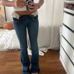 Levis  low waist bootcut jeans blå - Säljer ett par blå Levis jeans med låg midja och bootcut passform. Klassisk femficksmodell med snygga kontrastsömmar och dragkedja. Jeansen har en mörkblå tvätt och är tillverkade i slitstarkt denim. Perfekta för dig som gillar retrovibe och cool siluett.