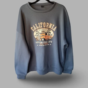 Grå sweatshirt California från SHEIN - Cool grå sweatshirt från SHEIN med stort tryck framtill som visar en orange retrobil och texten 'California Adventure Life'. Tröjan har rund hals, långa ärmar och loose passform. 