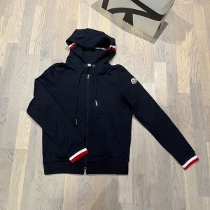 Marinblå moncler zip hoodie - Riktigt det moncler zip hoodie i mörkblå färg. Nyskick med tags kvar! Storlek S men passar även XS. Pris kan diskuteras vid snabb affär