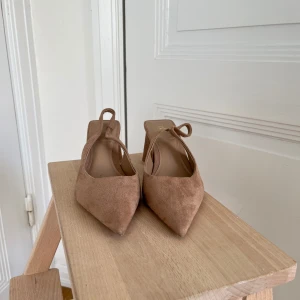 Beige mocka pumps från Zara strl 37 - Snygga beige pumps från Zara i mjuk mocka med spetsig tå och öppen häl. Strl 37. Skorna har en chunky klack.  Perfekta för dig som gillar stilrena detaljer. Använda en gång, som nya.