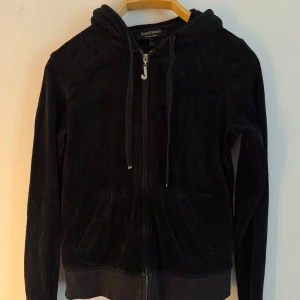 Juicy Couture hoodie  - Svart Juicy Couture hoodie med dragkedja och luva. Den har en dragkedja med ett "J" hänge och två fickor fram. Storlek M, men något liten i storleken, mer en S tycker jag. 