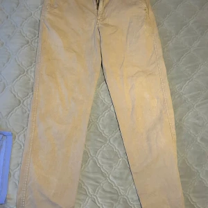 Beige chinos från Levi's i storlek S - Snygga beige chinos från Levi's i storlek S. Byxorna har klassisk rak passform, dragkedja och knapp framtill samt fickor både fram och bak. Materialet är mjukt och skönt, perfekt för en chill och stilren look. Levi's-logga syns på bakfickan.