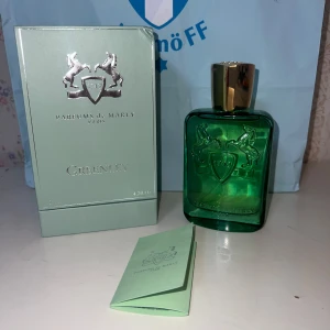 Parfums de Marly Greenley 125ml - Greenley från Parfums de Marly är en lyxig parfym i en grön glasflaska med silverdetaljer och guldfärgat lock. Flaskan har ett elegant reliefmönster med två hästar och en sköld. Kommer med originalkartong och folder. Volymen är 125ml.