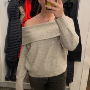 Beige offshoulder stickad tröja från H&M - Supermysig beige stickad tröja från H&M med bred ribbad kant och offshoulder-design. Mycket bra skick!