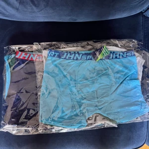 JHN Sport boxershorts 7 St - Två par boxershorts från JHN Sport, ena i marinblått med röd och ljusblå resår, andra i ljusblått med mörkblå resår. Snygg, sportig design med bred midja och logotyp. Mjukt och stretchigt material i bomull för skön passform.