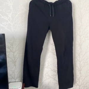 Svarta mjukisbyxor från Gina Tricot - Svarta mjukisbyxor från Gina Tricot, basically basics-kollektionen. De har elastisk midja med snörning och sidofickor. Byxorna är raka i modellen och gjorda i mjukt bomullsmaterial, perfekta för chill dagar eller häng med kompisar.