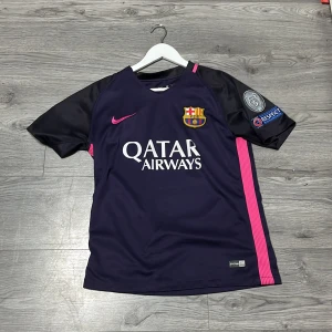 FC Barcelona Neymar Jr 11 Nike tröja storlek S - Snygg FC Barcelona matchtröja med Neymar Jr och nummer 11 på ryggen. Tröjan är mörkblå med svarta ärmar och rosa detaljer, inklusive Nike-logga och sidopaneler. Dri-FIT material för bästa komfort. Champions League-patch på ärmen och klubbmärke på bröstet.