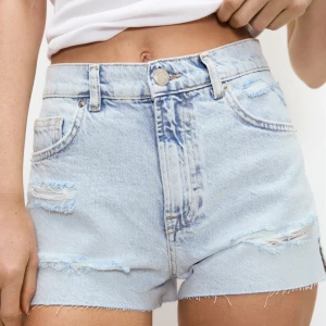 Ljusblå jeansshorts från Pull&Bear - Snygga ljusblå jeansshorts från Pull&Bear med slitna detaljer framtill. Storlek 36. Aldrig använda!! Frakt tillkommer 🚚