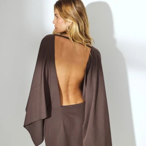 Brun kortklänning med öppen rygg - Snygg brun kortklänning med dramatisk öppen rygg och vida, svepande ärmar. Klänningen har en elegant och minimalistisk design. Perfekt för dig som vill sticka ut med en unik siluett och djup rygg.