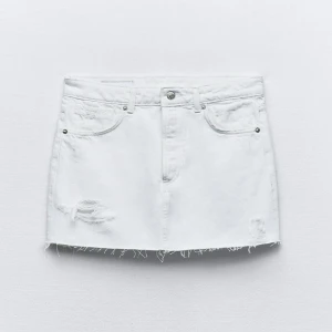 Vit mini jeanskjol med slitningar - Snygg vit kort jeanskjol med klassiska fickor fram och slitna detaljer. Kjolen har slitningar, fransig kant nedtill och knappstängning i midjan. Använd en gång och i nytt skick . Nypris 400