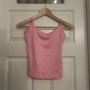 Rosa linnetopp med smala axelband - Säljer en söt rosa linnetopp med smala axelband och enkel design. Toppen har en mjuk, rundad halsringning och är tillverkad i ett skönt bomullsmaterial. Perfekt att matcha med jeans eller kjol för en chill look.