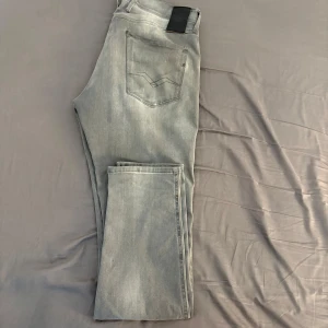 Replay Hyperflex Anbass grå jeans - Säljer ett par grå Replay Hyperflex Anbass jeans med snygg tvättad look. Modellen har klassiska fem fickor, raka ben och slim passform. Materialet är ”Hyperflex” jeans för extra komfort. Perfekt för dig som gillar stilrena och moderna jeans. Storlek 34/34.