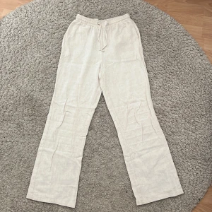 Beige linnebyxor från Grunt med snörning - Säljer ett par ljusbeige linnebyxor från Grunt i storlek M barn (ca 146-152). Byxorna har rak passform, elastisk midja med snörning, fick framtill och är tillverkade i ett luftigt linnematerial. Perfekta för chill dagar och sommarhäng. Snyggt och enkelt att matcha med sneakers eller sandaler. Säljer då de blivit för små för mig! Nypris ca 549. 