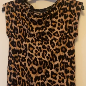 Leopardmönstrad topp från Lager 157, i storlek S - Cool topp från The Black Label Collection med leopardmönster i bruna, svarta och beige toner. Modellen är ärmlös. Perfekt för dig som vill sticka ut med ett djurmönstrat plagg. Aldrig använd.