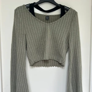 Grön croppad ribbad tröja  - Grön croppad tröja från Shein med v-ringning och långa ärmar. Tröjan är ribbad och har en mjuk, stickad känsla. Perfekt för dig som gillar en chill och trendig look. Passar snyggt till både jeans och kjol.